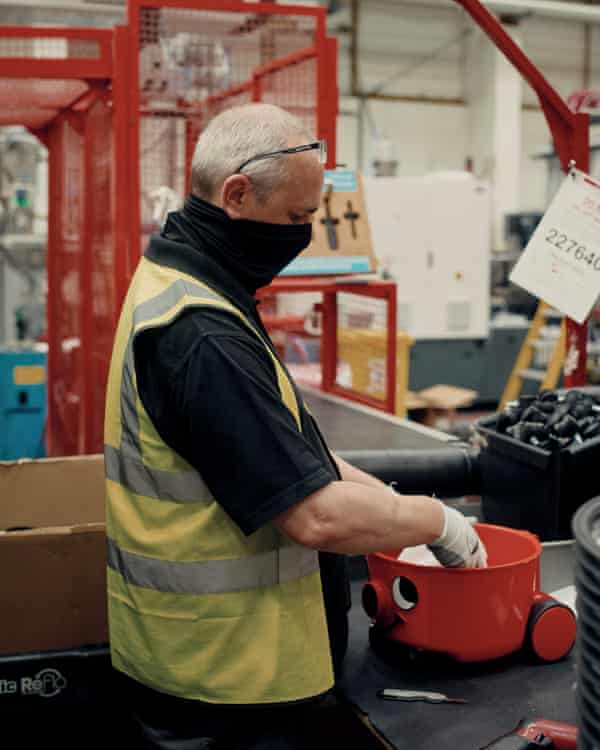 A Henry vacuum cleaner having its wheels and face attached on the assembly line.