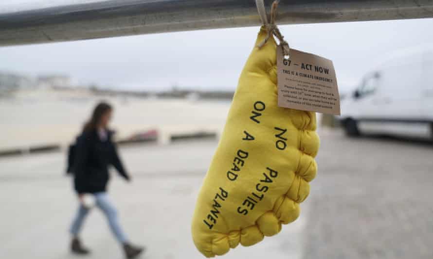 A man walks beside a fabric pillow in the shape of a Cornish Pastie put up by climate activists outside the G7 meeting in St Ives